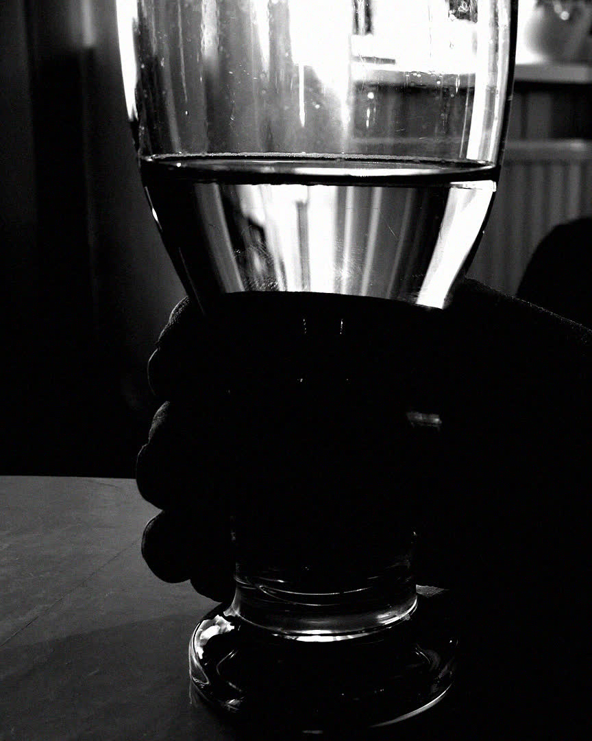 Mano sosteniendo una copa en un bar oscuro